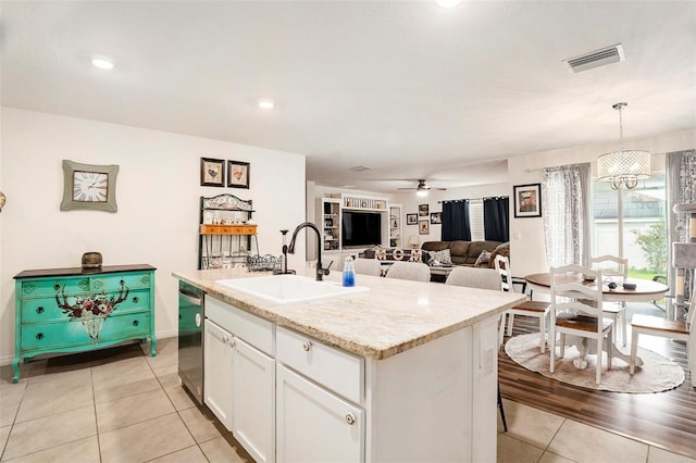 7639 Broad Pointe Dr, Zephyrhills, FL 33540 - kitchen featuring light tile patterned floors, white cabinets, a center island with sink, stainless steel dishwasher, and hanging light fixtures