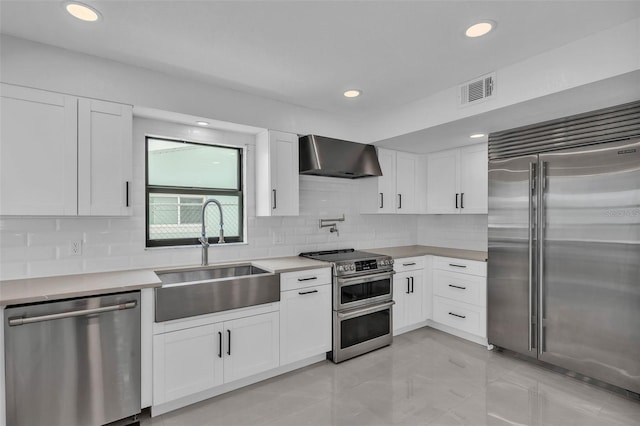 319 Midway Is, Clearwater Beach, FL 33767 - kitchen with appliances with stainless steel finishes, a sink, wall chimney exhaust hood, backsplash, and light countertops