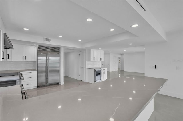 319 Midway Is, Clearwater Beach, FL 33767 - kitchen featuring stainless steel appliances, wine cooler, recessed lighting, backsplash, and white cabinets