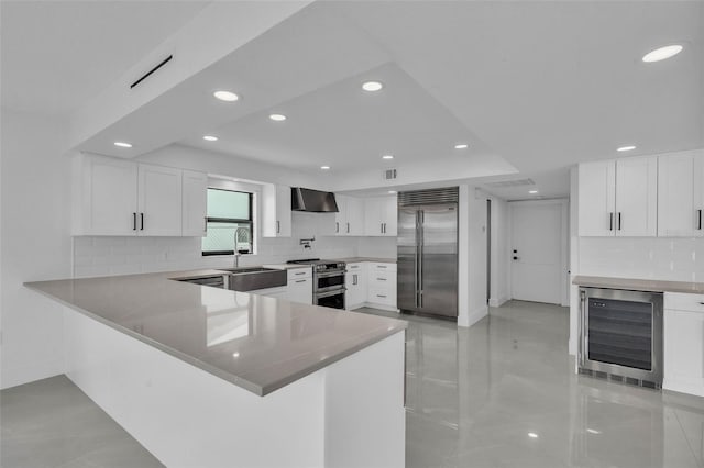319 Midway Is, Clearwater Beach, FL 33767 - kitchen with appliances with stainless steel finishes, a sink, wine cooler, wall chimney exhaust hood, and recessed lighting
