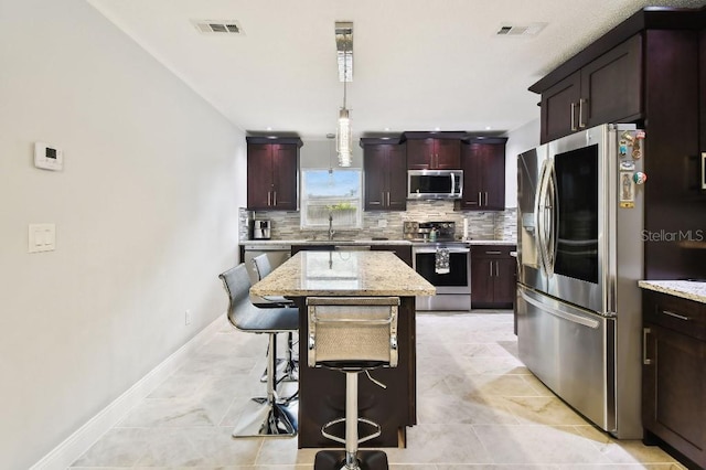 229 Temple Ave, Fern Park, FL 32730 - kitchen with appliances with stainless steel finishes, tasteful backsplash, a sink, a breakfast bar, and a kitchen island
