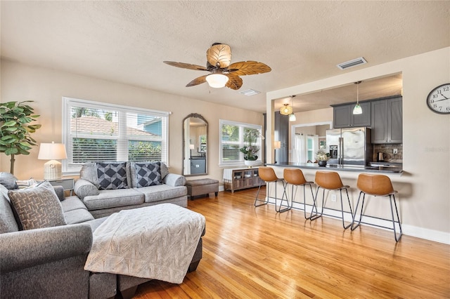 2709 Upton St S, Gulfport, FL 33711 - living room with light wood finished floors, plenty of natural light, ceiling fan, a textured ceiling, and baseboards