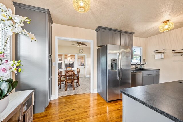 2709 Upton St S, Gulfport, FL 33711 - kitchen featuring stainless steel appliances, light wood-style floors, a sink, dark countertops, and a textured ceiling