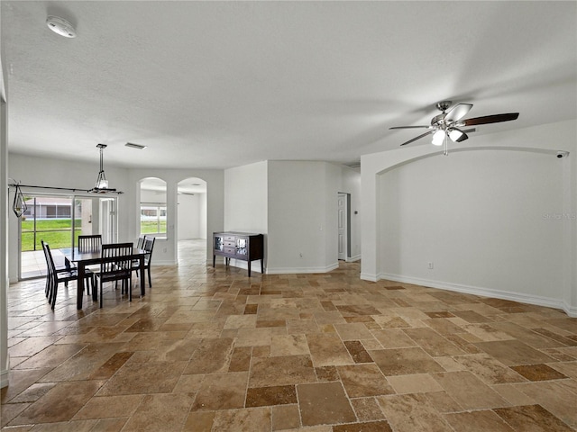 6957 Boulder Run Loop, Wesley Chapel, FL 33545 - living area featuring arched walkways, stone tile floors, a ceiling fan, and baseboards