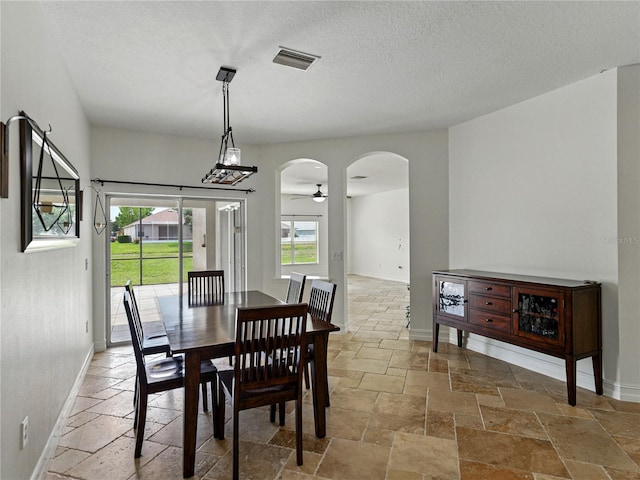 6957 Boulder Run Loop, Wesley Chapel, FL 33545 - dining area featuring stone tile floors, arched walkways, baseboards, and ceiling fan