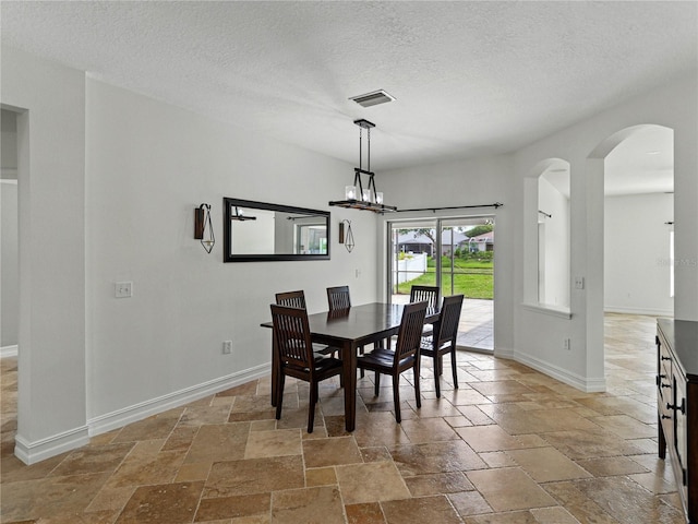 6957 Boulder Run Loop, Wesley Chapel, FL 33545 - dining area with stone tile floors, arched walkways, baseboards, and a textured ceiling