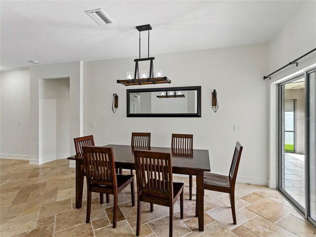 6957 Boulder Run Loop, Wesley Chapel, FL 33545 - dining room featuring stone tile floors, baseboards, and a chandelier