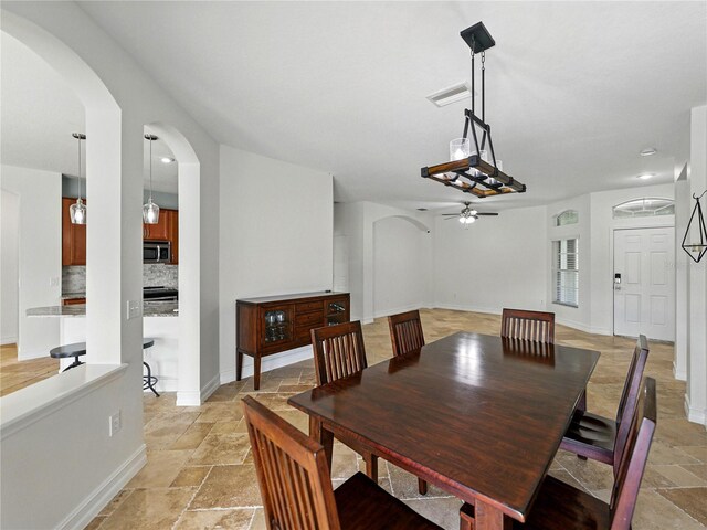 6957 Boulder Run Loop, Wesley Chapel, FL 33545 - dining room with stone tile floors, a ceiling fan, arched walkways, and baseboards