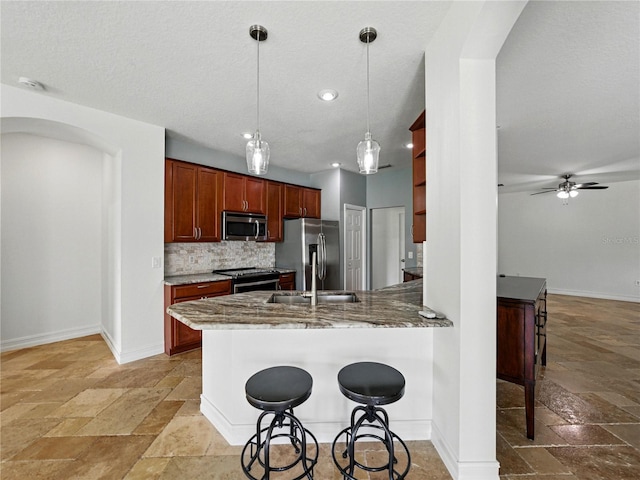6957 Boulder Run Loop, Wesley Chapel, FL 33545 - kitchen with appliances with stainless steel finishes, stone tile flooring, arched walkways, a peninsula, and recessed lighting