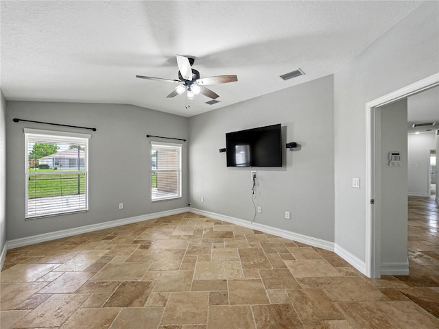 6957 Boulder Run Loop, Wesley Chapel, FL 33545 - unfurnished living room with stone tile flooring, a ceiling fan, plenty of natural light, baseboards, and vaulted ceiling