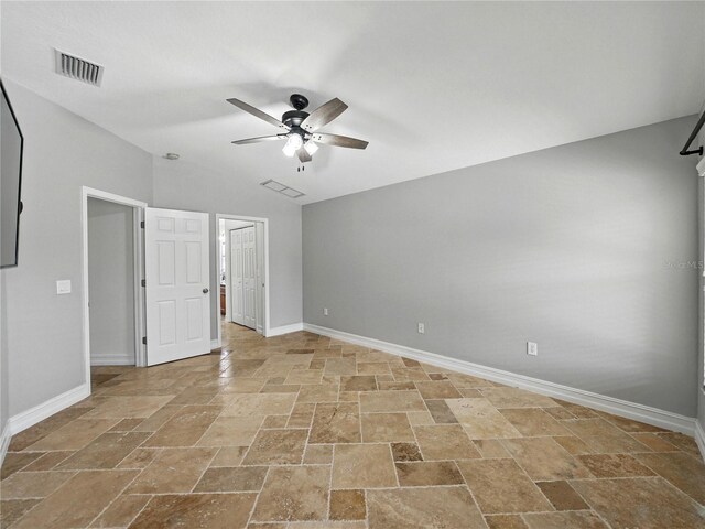 6957 Boulder Run Loop, Wesley Chapel, FL 33545 - unfurnished bedroom featuring stone tile flooring, baseboards, vaulted ceiling, and ceiling fan