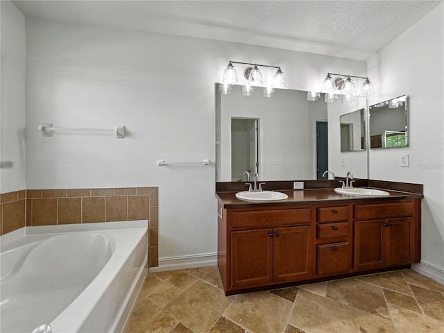 6957 Boulder Run Loop, Wesley Chapel, FL 33545 - bathroom with a bath, double vanity, stone finish floors, baseboards, and a textured ceiling