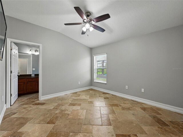 6957 Boulder Run Loop, Wesley Chapel, FL 33545 - unfurnished bedroom with stone tile flooring, vaulted ceiling, baseboards, connected bathroom, and a ceiling fan