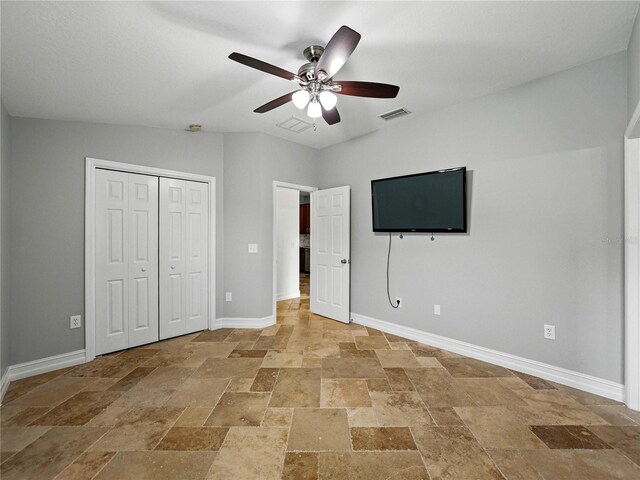 6957 Boulder Run Loop, Wesley Chapel, FL 33545 - unfurnished bedroom featuring stone tile floors, baseboards, ceiling fan, and a closet