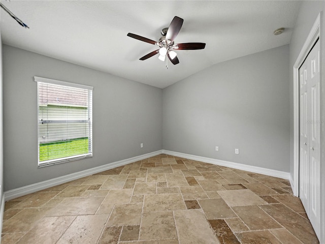 6957 Boulder Run Loop, Wesley Chapel, FL 33545 - unfurnished bedroom with stone tile flooring, vaulted ceiling, a closet, baseboards, and ceiling fan