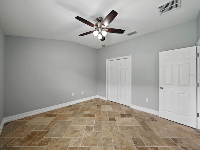 6957 Boulder Run Loop, Wesley Chapel, FL 33545 - unfurnished bedroom featuring stone tile flooring, baseboards, a closet, a ceiling fan, and vaulted ceiling