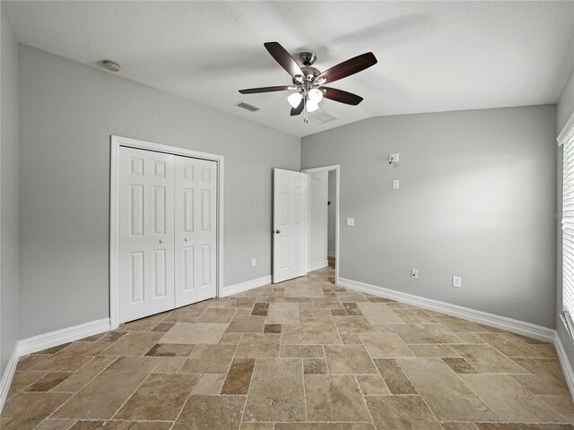 6957 Boulder Run Loop, Wesley Chapel, FL 33545 - unfurnished bedroom with stone tile floors, baseboards, a closet, a ceiling fan, and lofted ceiling