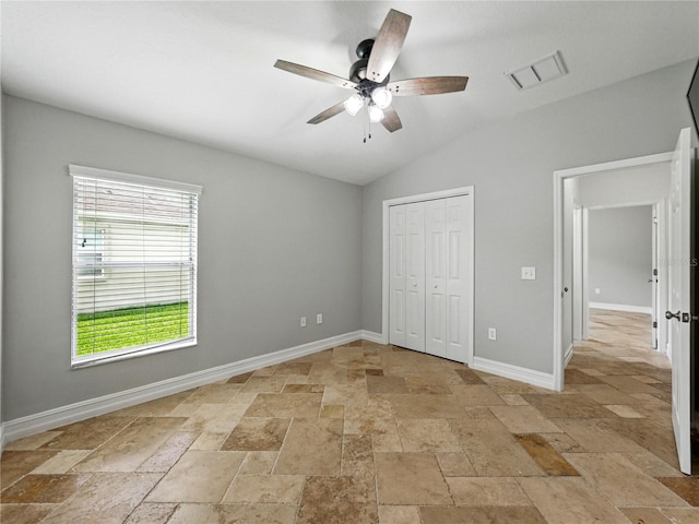6957 Boulder Run Loop, Wesley Chapel, FL 33545 - unfurnished bedroom featuring stone tile flooring, vaulted ceiling, a closet, baseboards, and ceiling fan