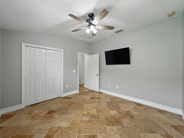 6957 Boulder Run Loop, Wesley Chapel, FL 33545 - unfurnished bedroom with stone tile flooring, baseboards, a closet, a ceiling fan, and vaulted ceiling