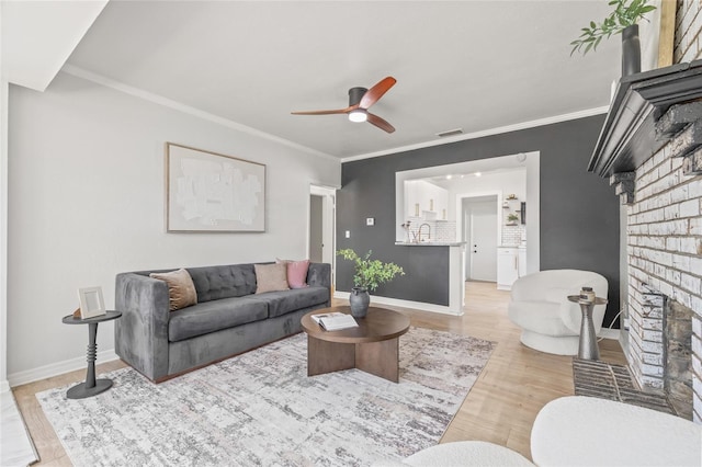 5622 Tangerine Ave S, Gulfport, FL 33707 - living room with a brick fireplace, a ceiling fan, light wood-style flooring, baseboards, and ornamental molding