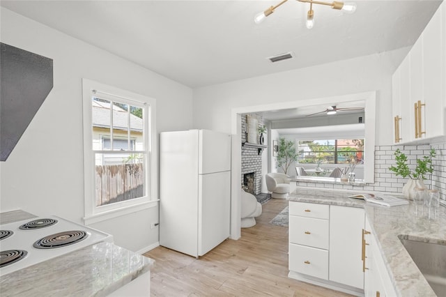 5622 Tangerine Ave S, Gulfport, FL 33707 - kitchen with white appliances, a fireplace, decorative backsplash, light wood-style floors, and white cabinetry