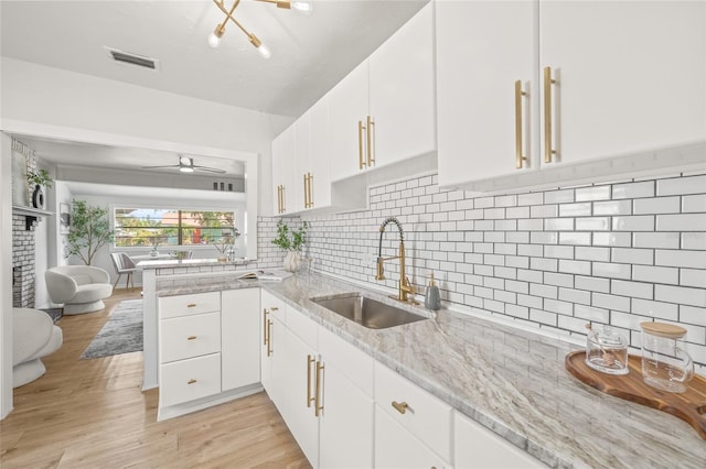 5622 Tangerine Ave S, Gulfport, FL 33707 - kitchen with a sink, a peninsula, white cabinets, and light wood-style floors