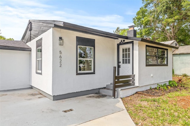 5622 Tangerine Ave S, Gulfport, FL 33707 - view of front of home featuring entry steps, a chimney, a patio area, and stucco siding