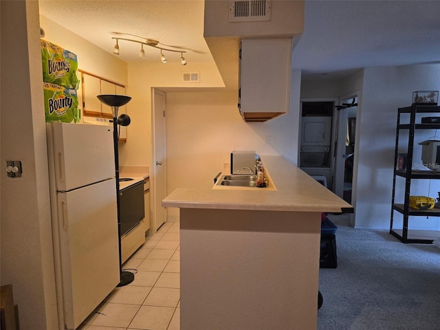 9100 Mlk St N Unit 503, Saint Petersburg, FL 33702 - kitchen featuring white appliances, stacked washer / dryer, a peninsula, light countertops, and a sink
