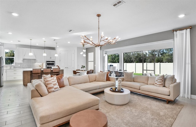 1576 Valier Pt, Zephyrhills, FL 33541 - living room featuring plenty of natural light, a chandelier, light wood finished floors, and recessed lighting