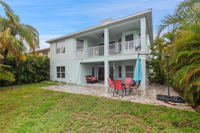 6416 Grenada Island Ave, Apollo Beach, FL 33572 - rear view of house featuring a balcony, ceiling fan, stucco siding, a lawn, and a patio area