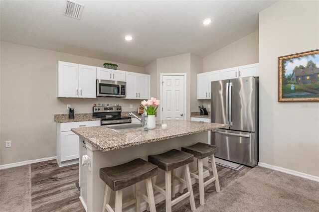 1368 Axel Cir, Winter Haven, FL 33880 - kitchen featuring stainless steel appliances, white cabinetry, an island with sink, a kitchen breakfast bar, and recessed lighting