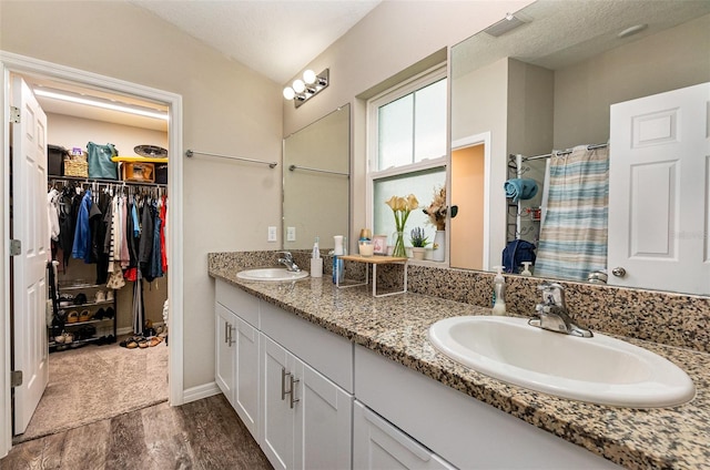 1368 Axel Cir, Winter Haven, FL 33880 - full bathroom with double vanity, a spacious closet, a shower with shower curtain, and wood finished floors