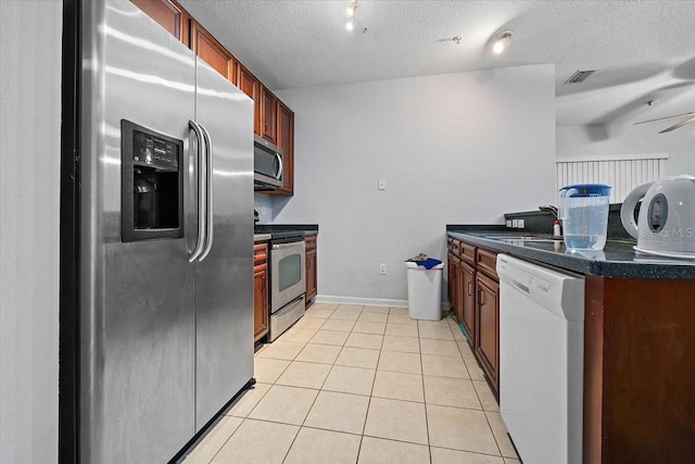 4998 Key Lime Dr Unit 103, Jacksonville, FL 32256 - kitchen featuring appliances with stainless steel finishes, dark countertops, light tile patterned flooring, a textured ceiling, and a sink