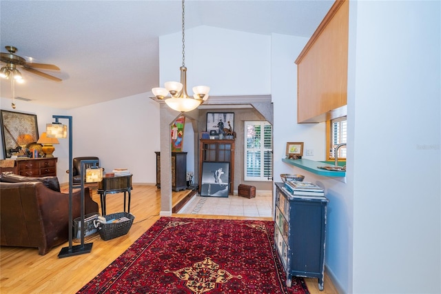 4783 Palermo Ct NE, Saint Petersburg, FL 33703 - living room featuring a chandelier, ceiling fan, lofted ceiling, and light wood-style flooring