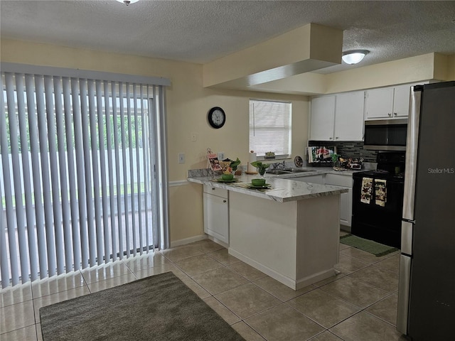 505 Innergary Pl, Valrico, FL 33594 - kitchen featuring appliances with stainless steel finishes, a peninsula, plenty of natural light, a sink, and a textured ceiling