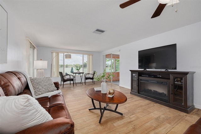 8014 Lotus Dr, Port Richey, FL 34668 - living room featuring a ceiling fan, light wood-type flooring, and a glass covered fireplace