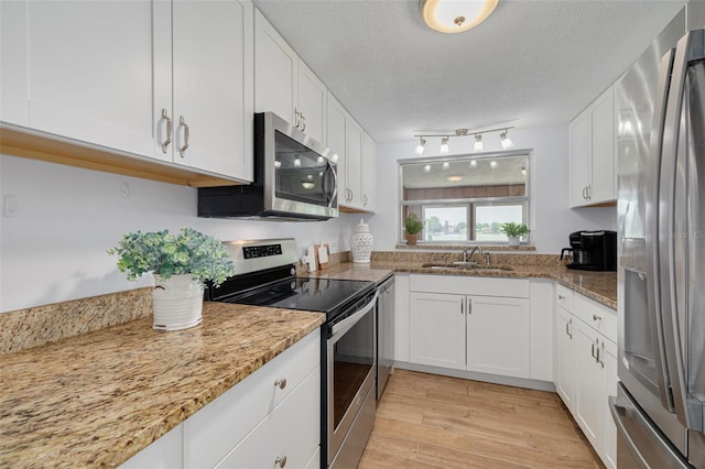 8014 Lotus Dr, Port Richey, FL 34668 - kitchen with stainless steel appliances, white cabinetry, light wood-type flooring, a textured ceiling, and light stone countertops