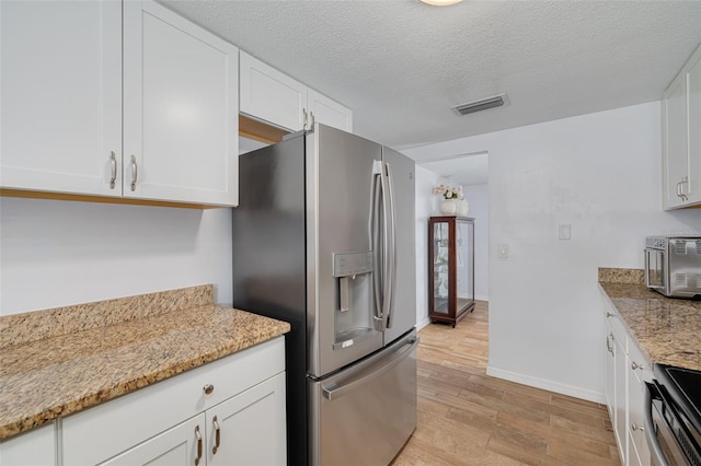 8014 Lotus Dr, Port Richey, FL 34668 - kitchen featuring stainless steel appliances, light wood-style floors, white cabinetry, light stone countertops, and a textured ceiling