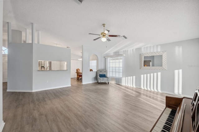 4411 Whitton Way, New Port Richey, FL 34653 - unfurnished living room with wood finished floors, vaulted ceiling, ceiling fan, baseboards, and a textured ceiling