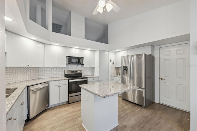 4411 Whitton Way, New Port Richey, FL 34653 - kitchen with appliances with stainless steel finishes, a ceiling fan, white cabinetry, tasteful backsplash, and a towering ceiling