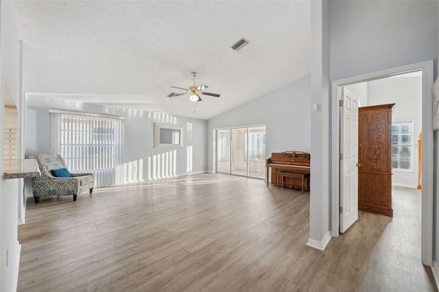4411 Whitton Way, New Port Richey, FL 34653 - unfurnished living room with a ceiling fan, wood finished floors, vaulted ceiling, baseboards, and a textured ceiling