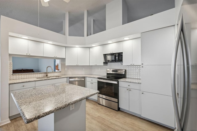 4411 Whitton Way, New Port Richey, FL 34653 - kitchen with stainless steel appliances, a sink, a kitchen island, decorative backsplash, and high vaulted ceiling