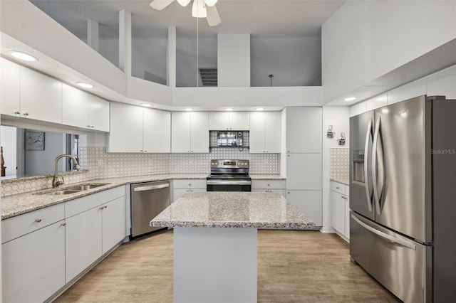 4411 Whitton Way, New Port Richey, FL 34653 - kitchen with appliances with stainless steel finishes, a sink, white cabinets, a high ceiling, and light wood-type flooring