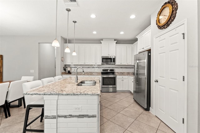 18620 Rococo Rd, Spring Hill, FL 34610 - kitchen featuring stainless steel appliances, a sink, light tile patterned floors, a kitchen bar, and white cabinetry
