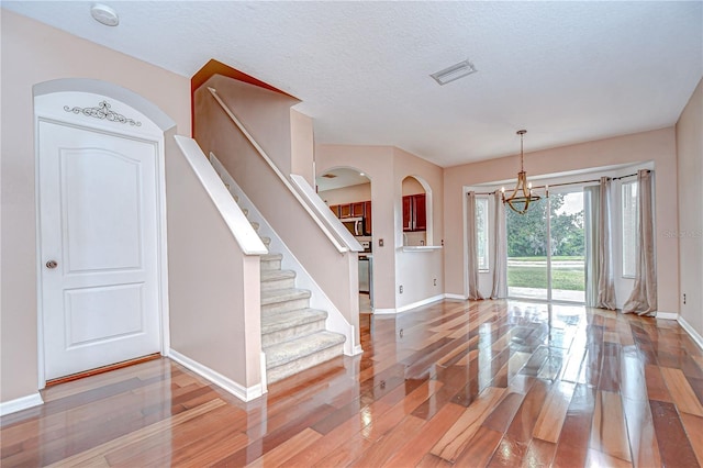 4227 Bethpage Ct, Wesley Chapel, FL 33543 - entrance foyer with baseboards, wood finished floors, a chandelier, arched walkways, and stairway