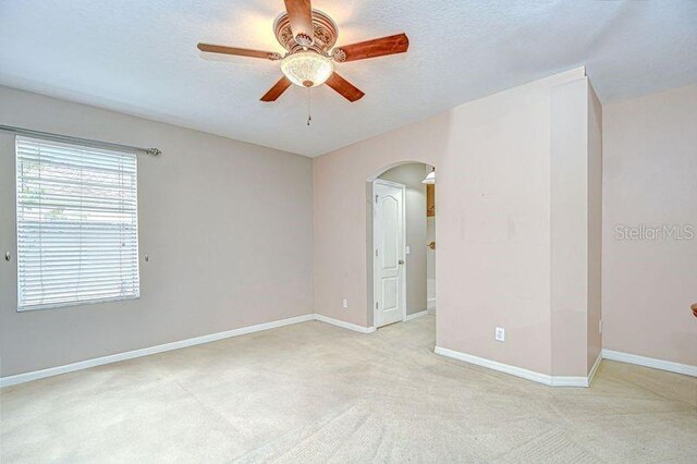 4227 Bethpage Ct, Wesley Chapel, FL 33543 - empty room with arched walkways, a ceiling fan, light colored carpet, baseboards, and a textured ceiling
