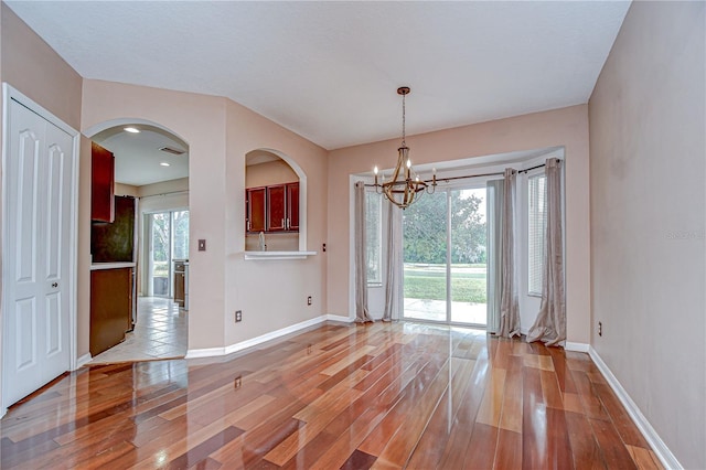 4227 Bethpage Ct, Wesley Chapel, FL 33543 - unfurnished dining area featuring a chandelier, light wood-style floors, baseboards, and arched walkways