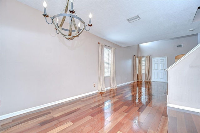 4227 Bethpage Ct, Wesley Chapel, FL 33543 - spare room featuring a chandelier, wood finished floors, baseboards, and a textured ceiling