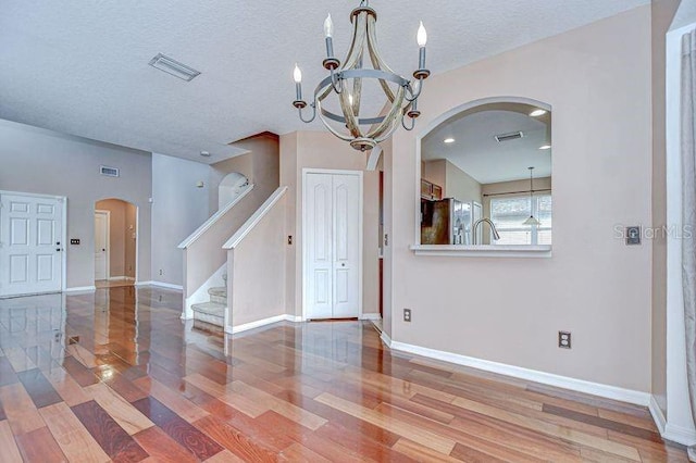 4227 Bethpage Ct, Wesley Chapel, FL 33543 - unfurnished room featuring arched walkways, wood finished floors, a chandelier, stairs, and baseboards
