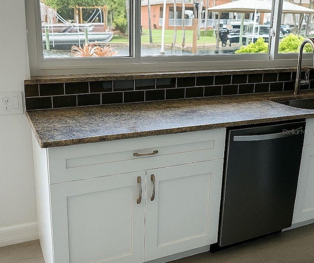 5264 S Spy Glass Pt, Homosassa, FL 34448 - kitchen view of dishwasher, dark countertops, tasteful backsplash, and white cabinets